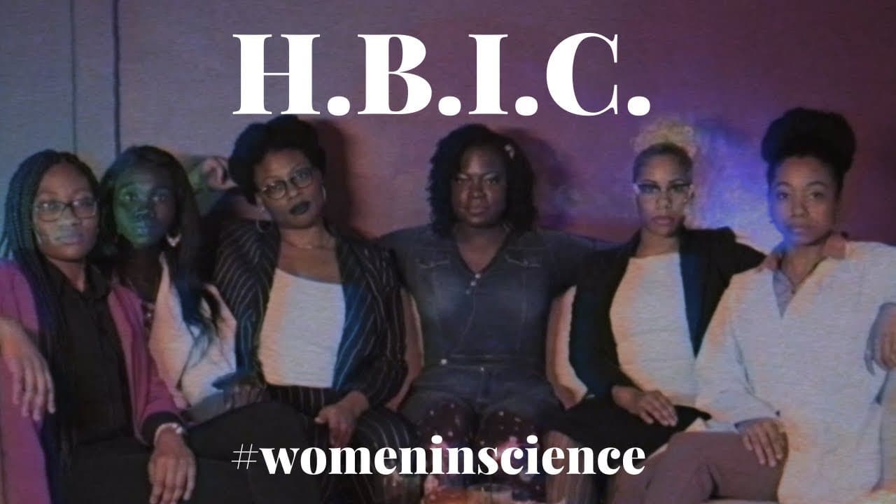 Six women sit side by side on a couch in purple and blue light, under a large white H.B.I.C. title and the hashtag #womeninscience.