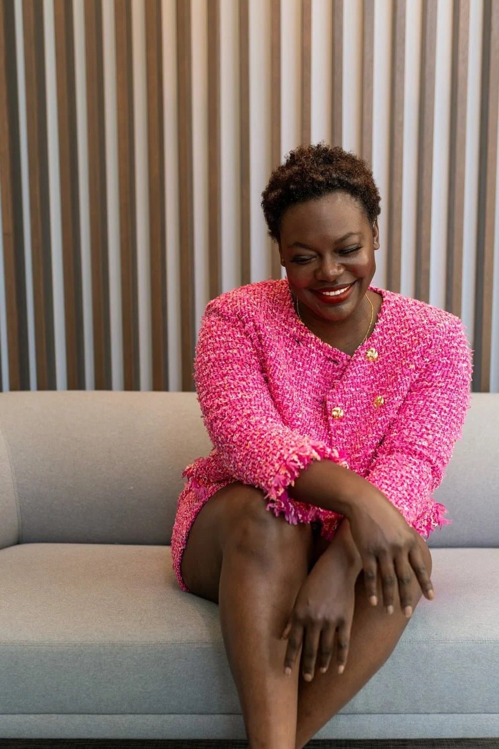 Dr. Raven Baxter in a pink tweed jacket, seated portrait