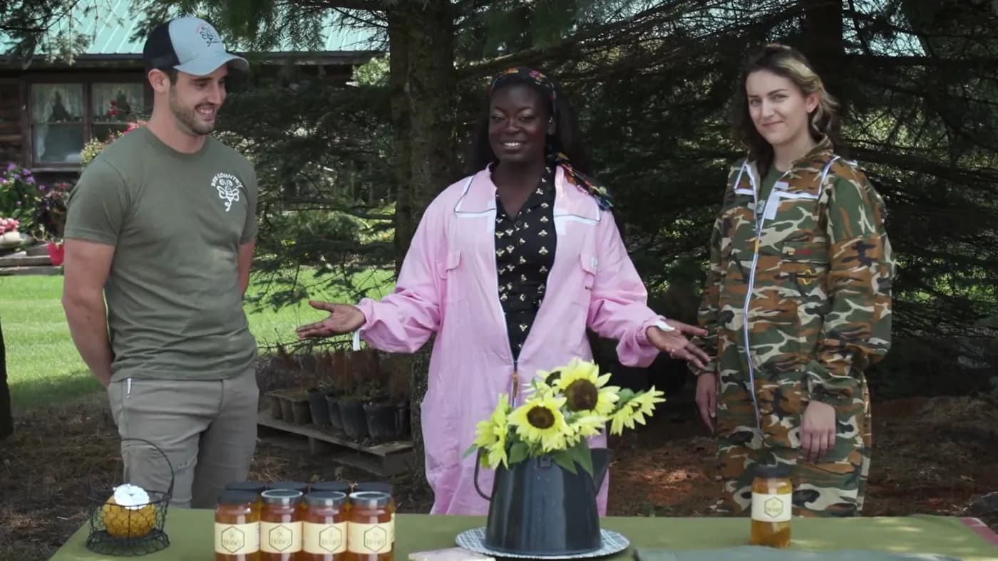 Dr. Raven Baxter in a pink beekeeping suit presenting jars of honey at a table with sunflowers, from Nerdy Jobs Episode 2