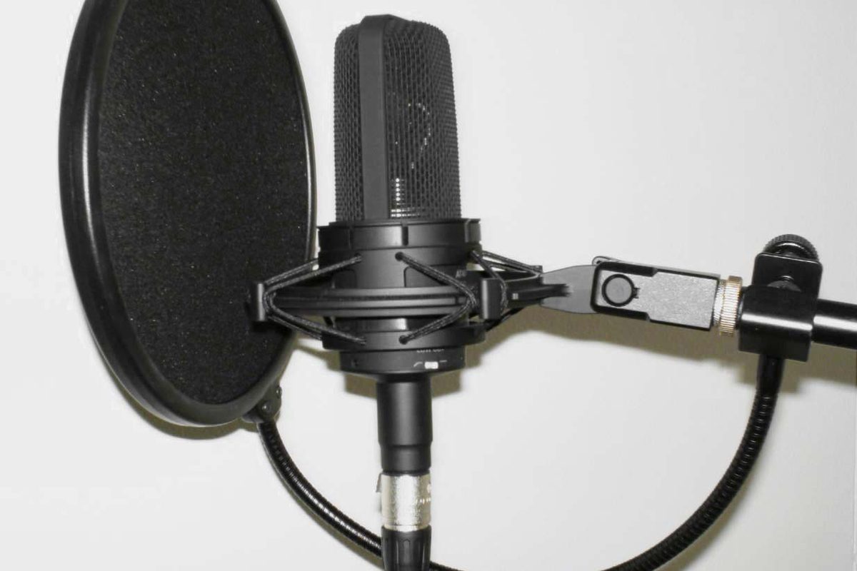 Studio condenser microphone on a boom arm behind a pop filter