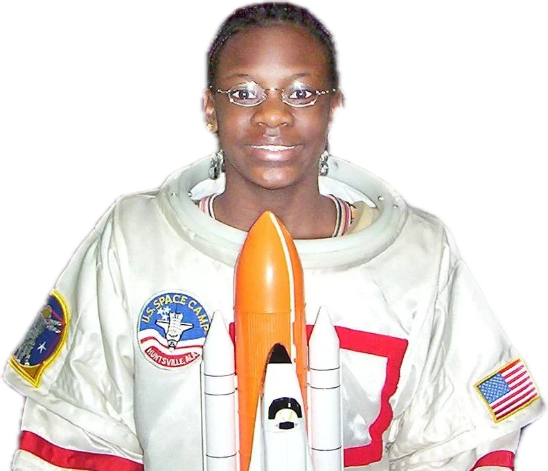 Raven as a sixth grader in a Space Camp flight suit, holding a space shuttle model, 2004